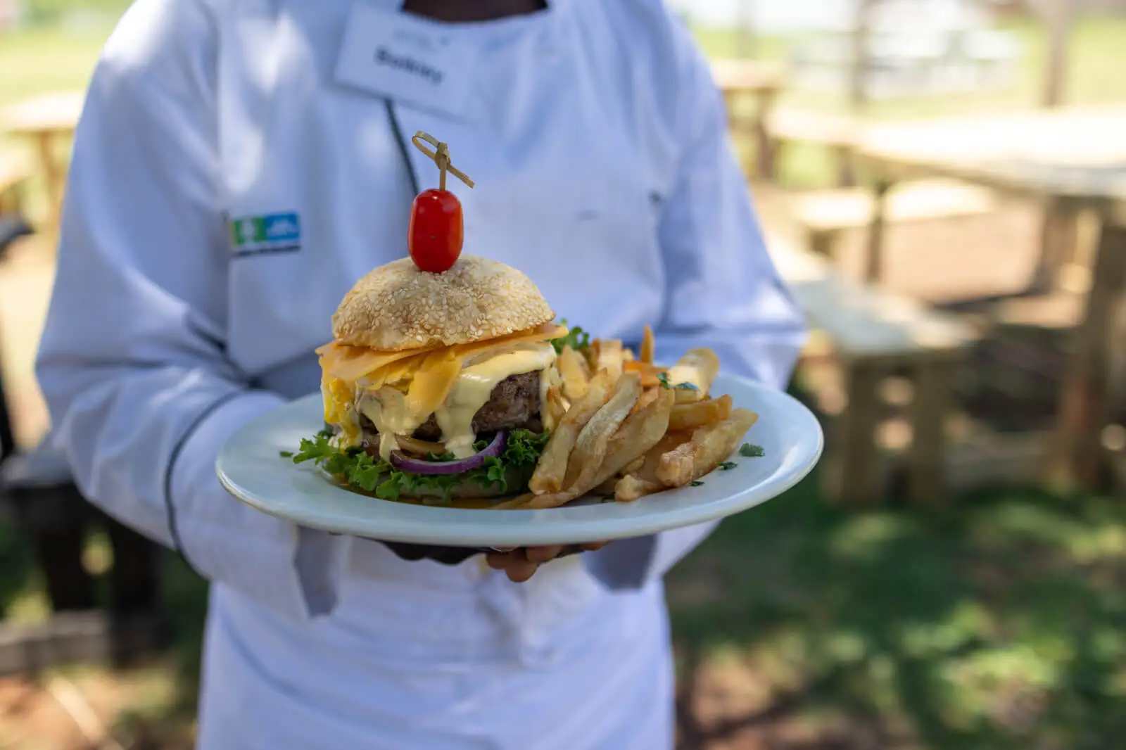 A chef holding a burger and chips