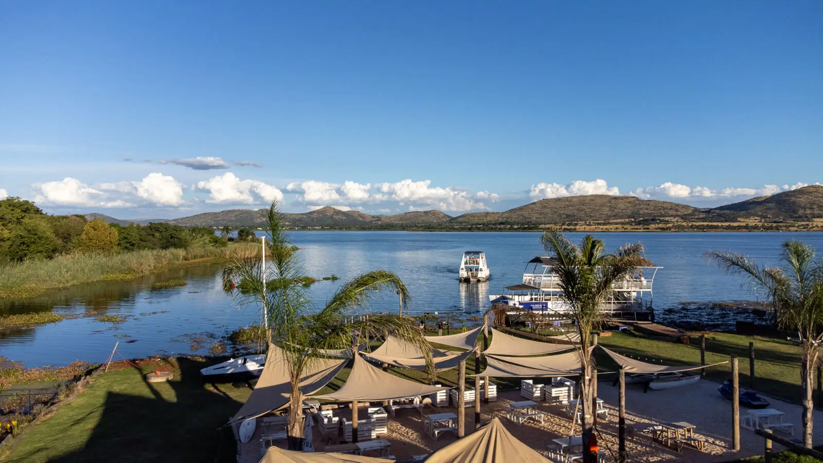 The harbour's palms and beach, with the dam and the Magaliesberg behind
